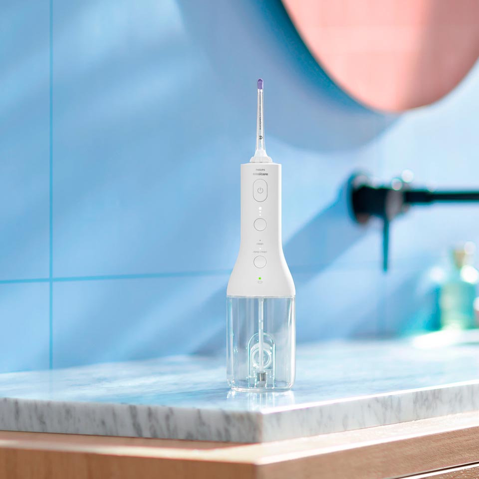 Mano alcanzando un dispositivo Power Flosser en una superficie