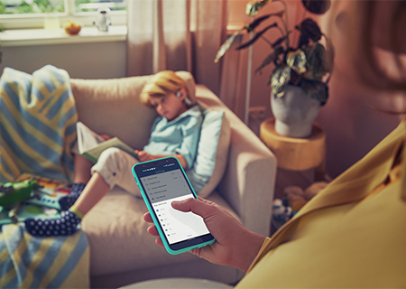 Madre controlando los auriculares para ni&ntilde;os Philips de su hijo con el tel&eacute;fono