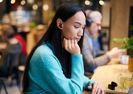 Mujer estudiando en una cafeter&iacute;a usando auriculares inal&aacute;mbricos con cancelaci&oacute;n de ruido Philips T3508