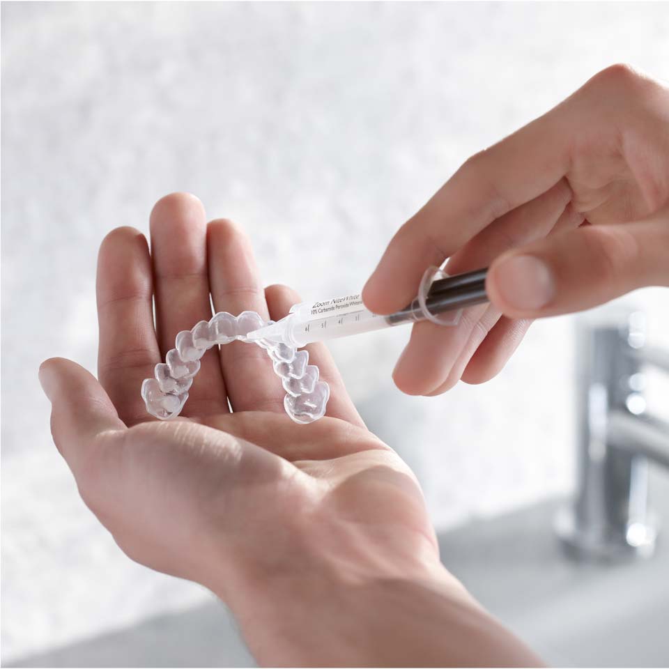 Paciente aplicando gel blanqueador en la bandeja personalizada