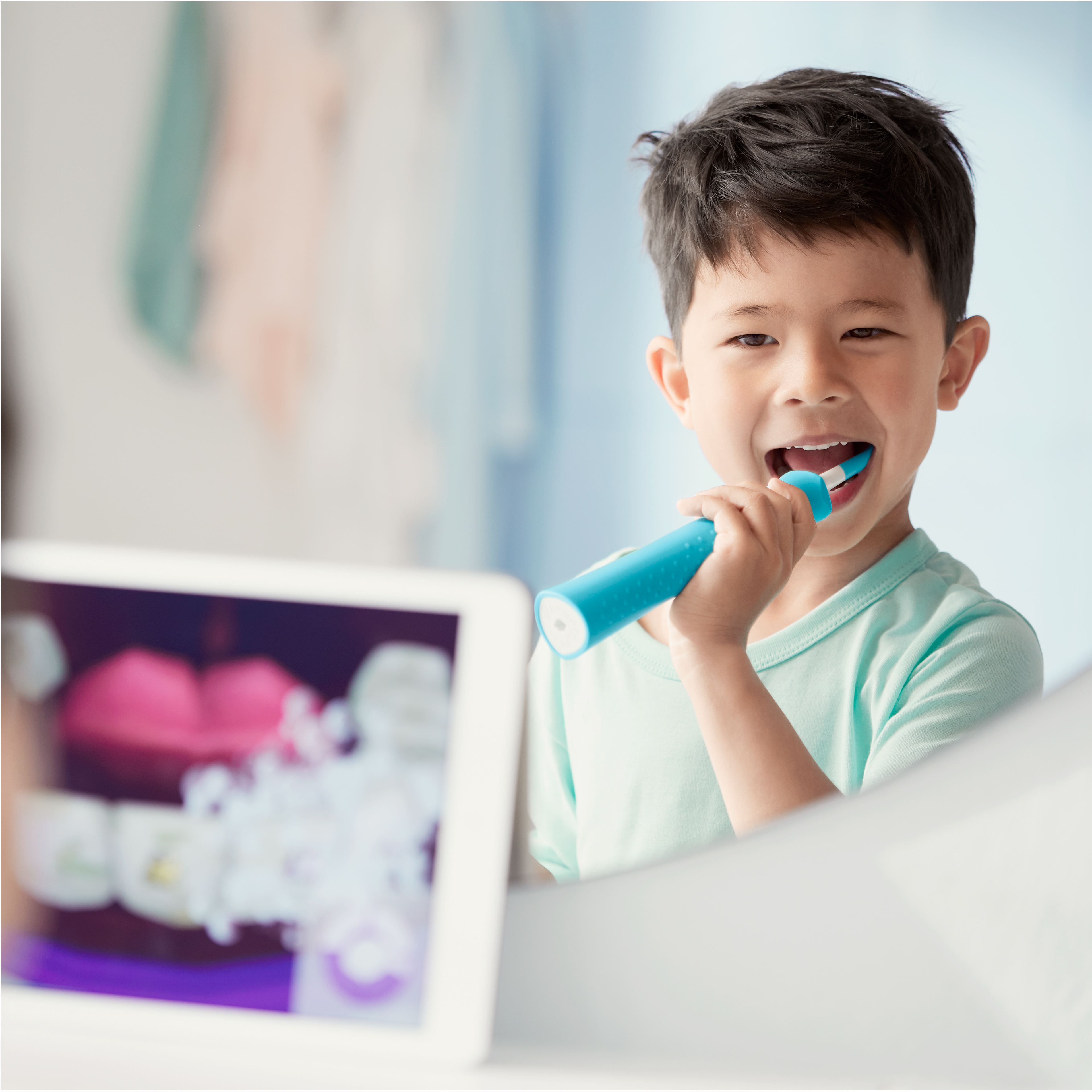 Un ni&ntilde;o usando un cepillo dental el&eacute;ctrico Sonicare for Kids mientras mira la aplicaci&oacute;n Sonicare for Kids