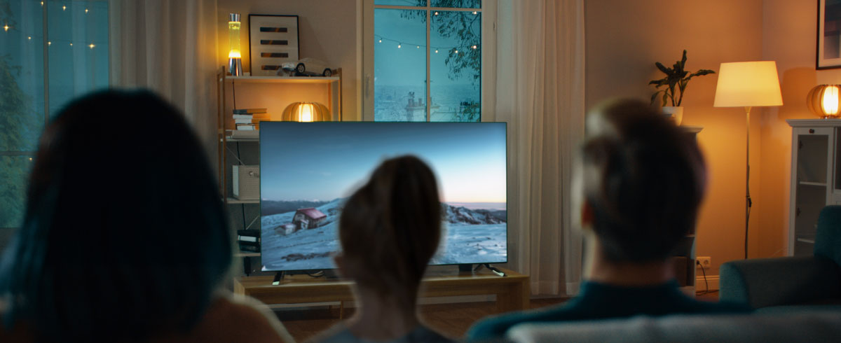 Familia reunida en un sal&oacute;n mira una televisi&oacute;n de pantalla grande