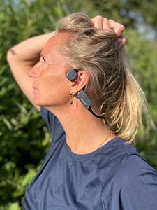 Mujer con los auriculares Bluetooth de conducci&oacute;n &oacute;sea de Philips