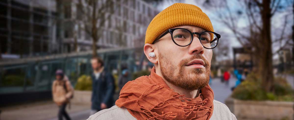 Foto de primer plano de un hombre con auriculares inal&aacute;mbricos verdaderos