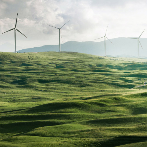 Un parque e&oacute;lico con colinas verdes para representar la energ&iacute;a limpia y la sostenibilidad en las empresas.